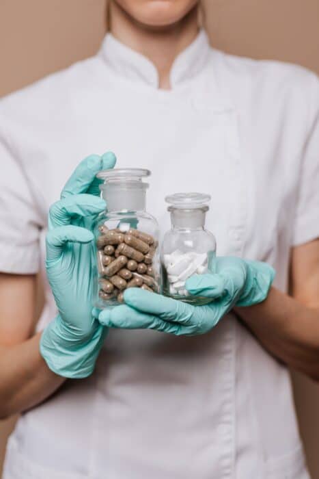  pharmacy technician holding jar of capsules